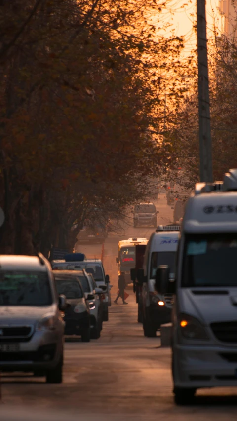 many vehicles parked along a city street during sunset