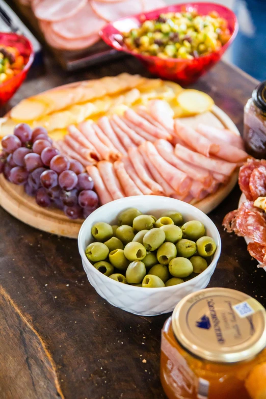 a table full of food with bottles of jam and cheese