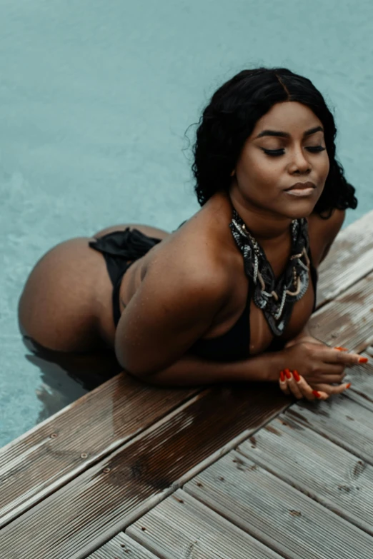 a woman poses on the end of a dock near a swimming pool