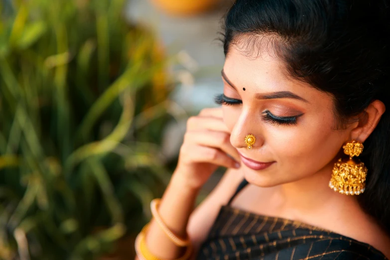 the woman is wearing gold jewelry and looking away from the camera