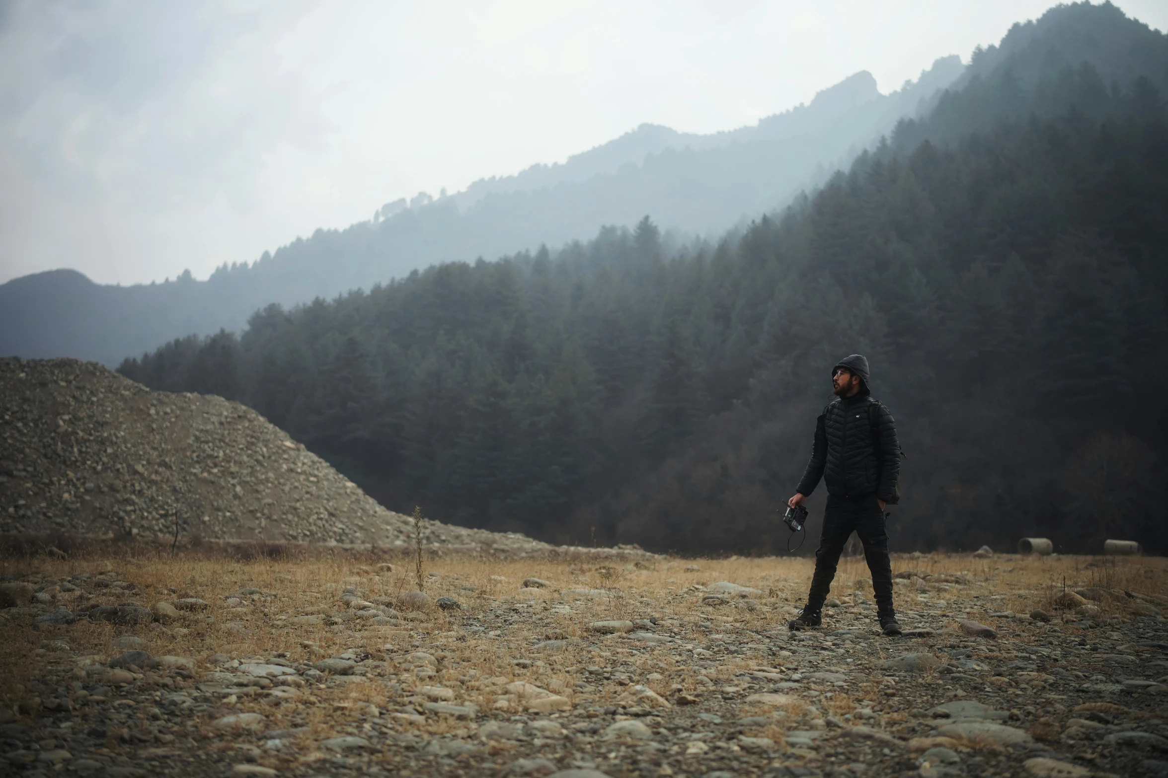 a man wearing a jacket and standing in front of hills