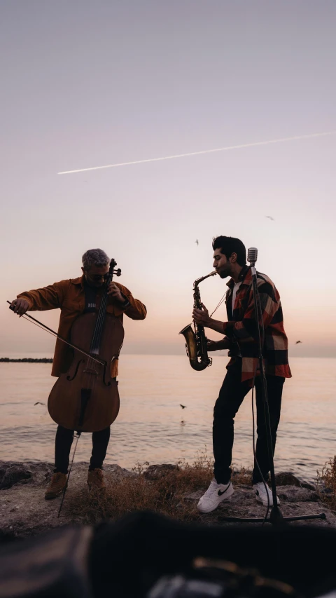 two men standing next to each other in front of the ocean