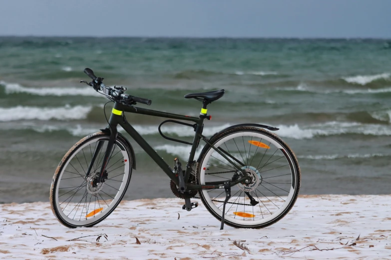 a bicycle sitting on the sand near water