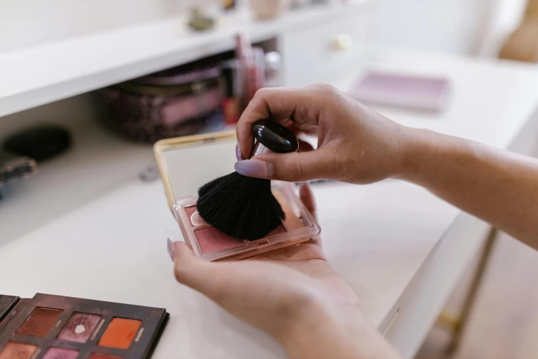 woman's hand on top of a compact compact in front of a mirror