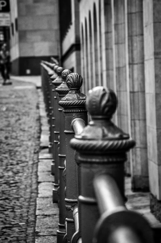 line of fence posts along a street, with building in the background