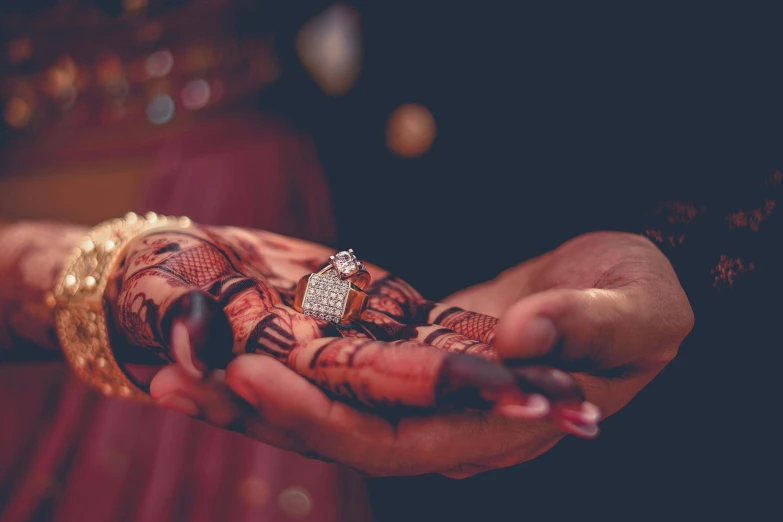 person's hands and ring adorned with a diamond