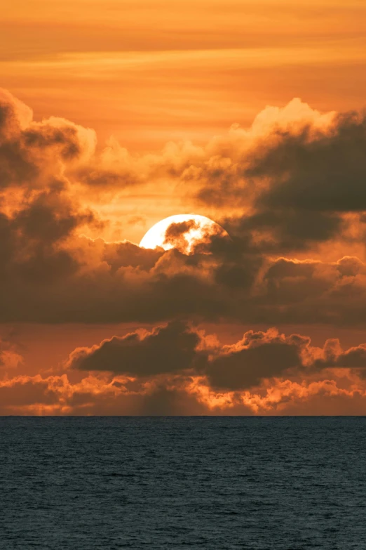 the sun setting behind a cloud filled sky