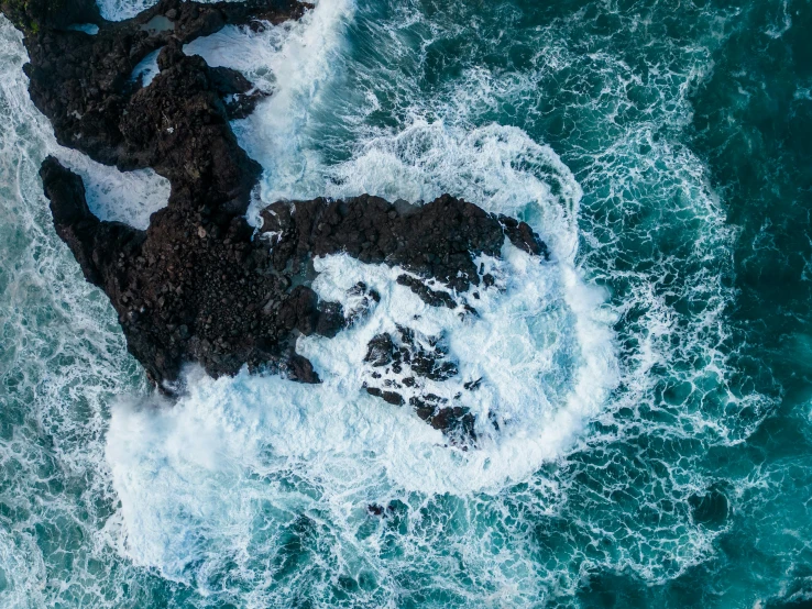 a rocky shoreline with waves on the rocks and green water