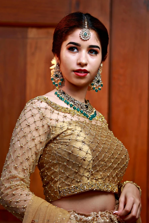 a woman in a golden lehenga with jewellery on her head