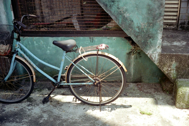 a bicycle leaning against a blue wall on the sidewalk