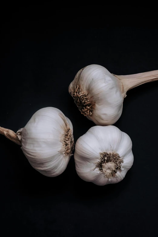 some garlic on a dark table next to some leaves