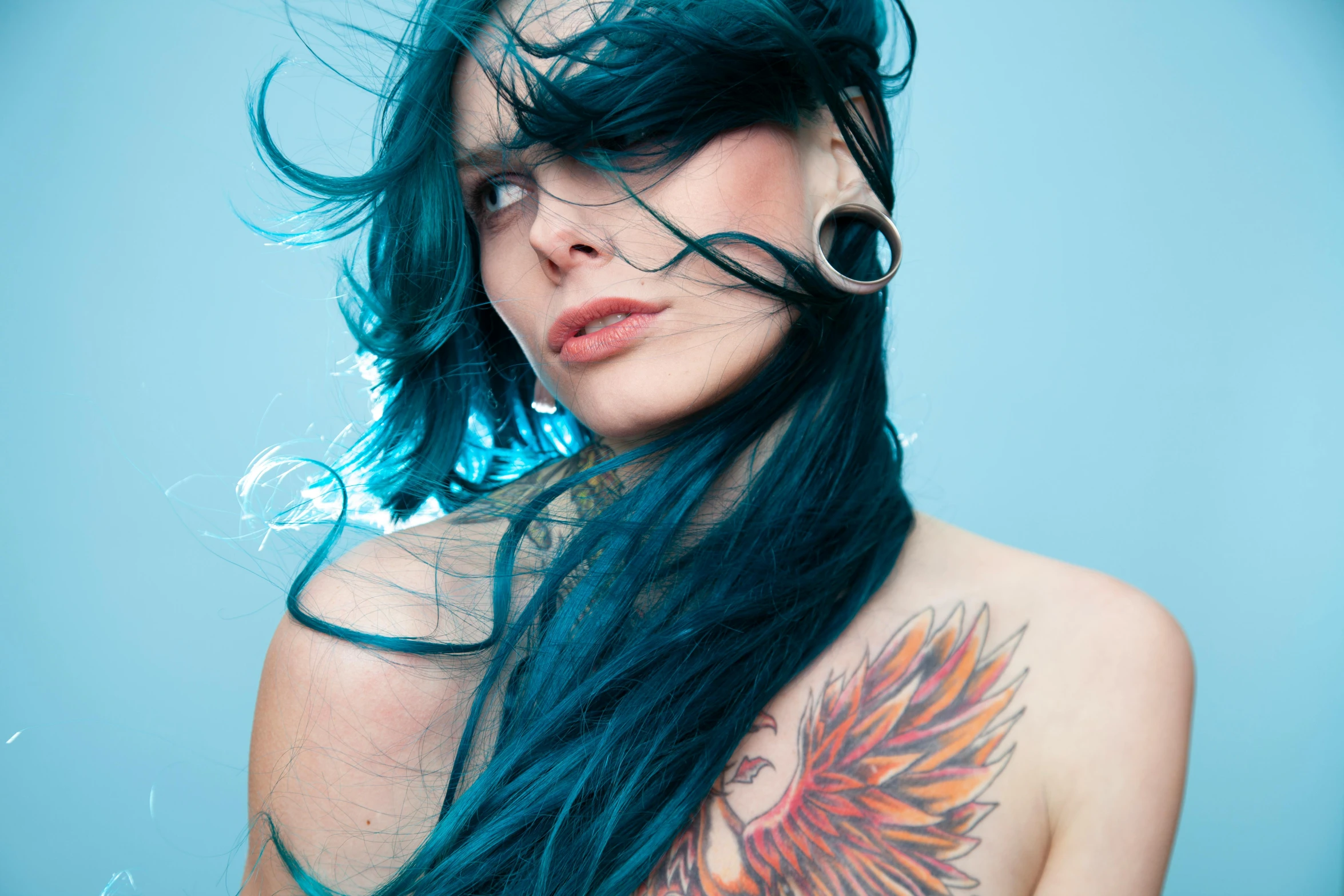 woman with blue hair with bird tattooed on back