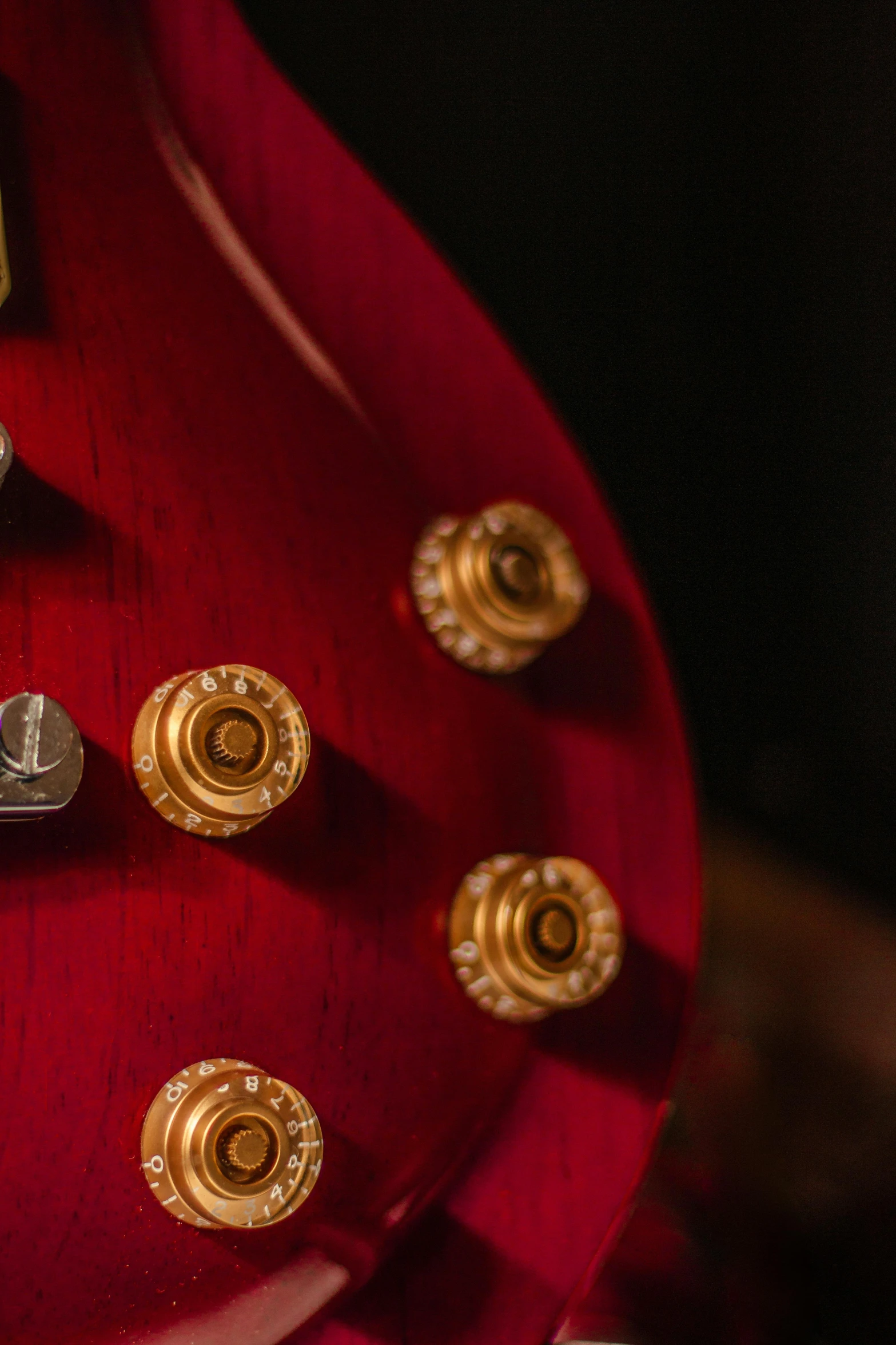 a red guitar with gold s sitting on a shelf