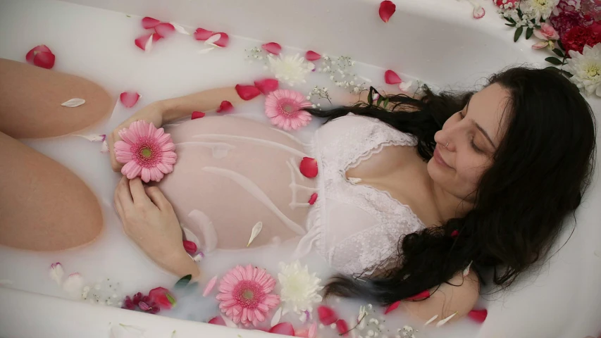 a pretty young lady laying in a bath tub surrounded by flowers