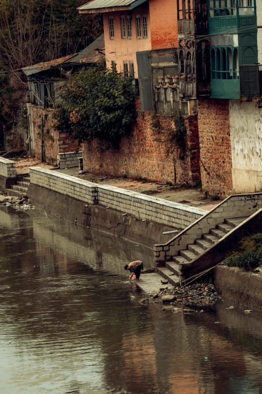 an old concrete walkway near a river leading to several buildings