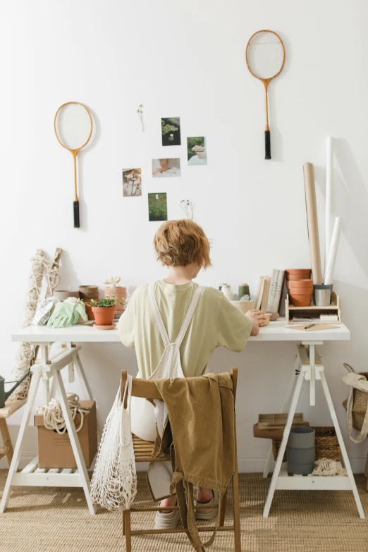 the woman sits in front of the white table holding bags