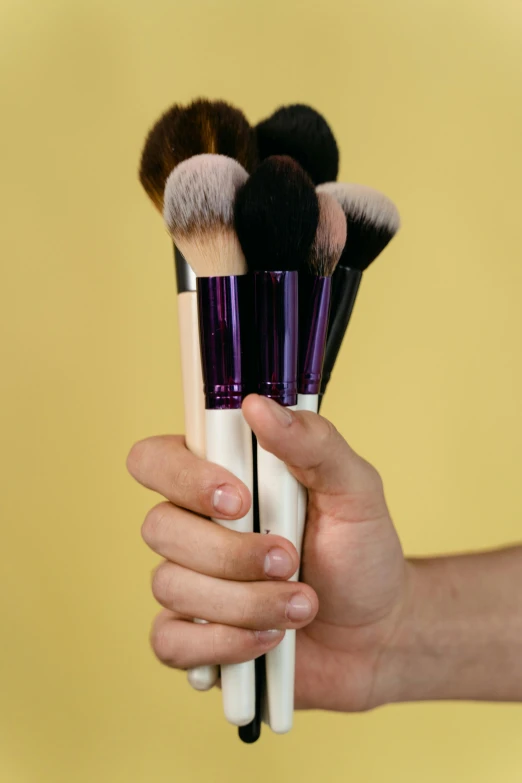 a person holding five brushes in their hands