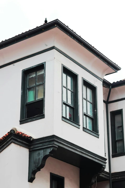 a white building with a small window near many bushes