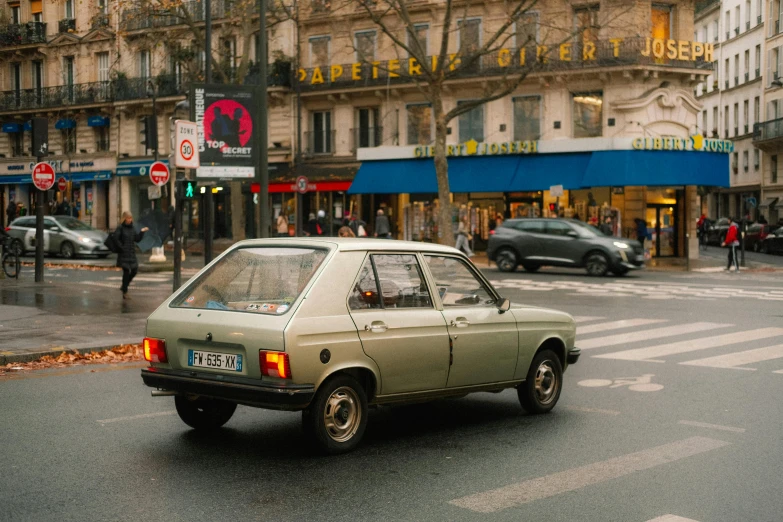 an older, narrow car travels down the road with other cars in the background