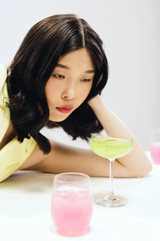 a woman with a pink and green drink looking sad