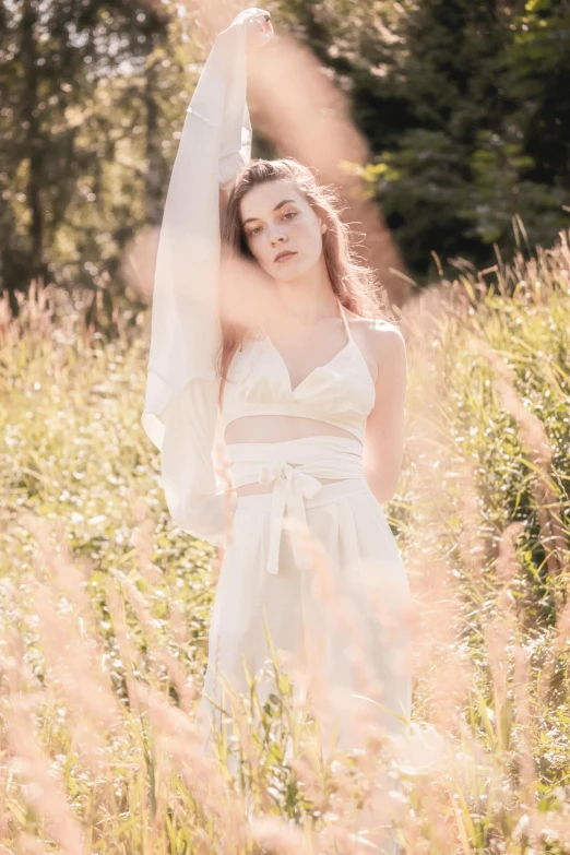 woman in white dress with veil standing in grass