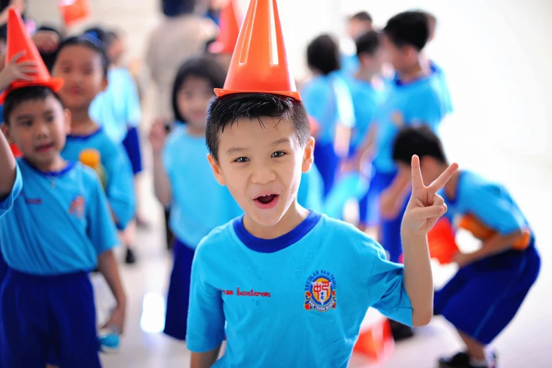 the children are dressed in bright blue shirts and one child wearing a plastic orange party hat