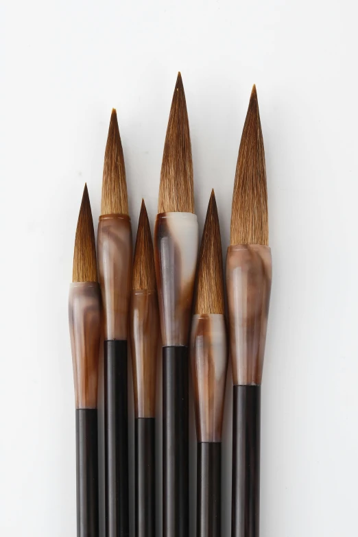 five black, silver and gold brushes sticking out of each other