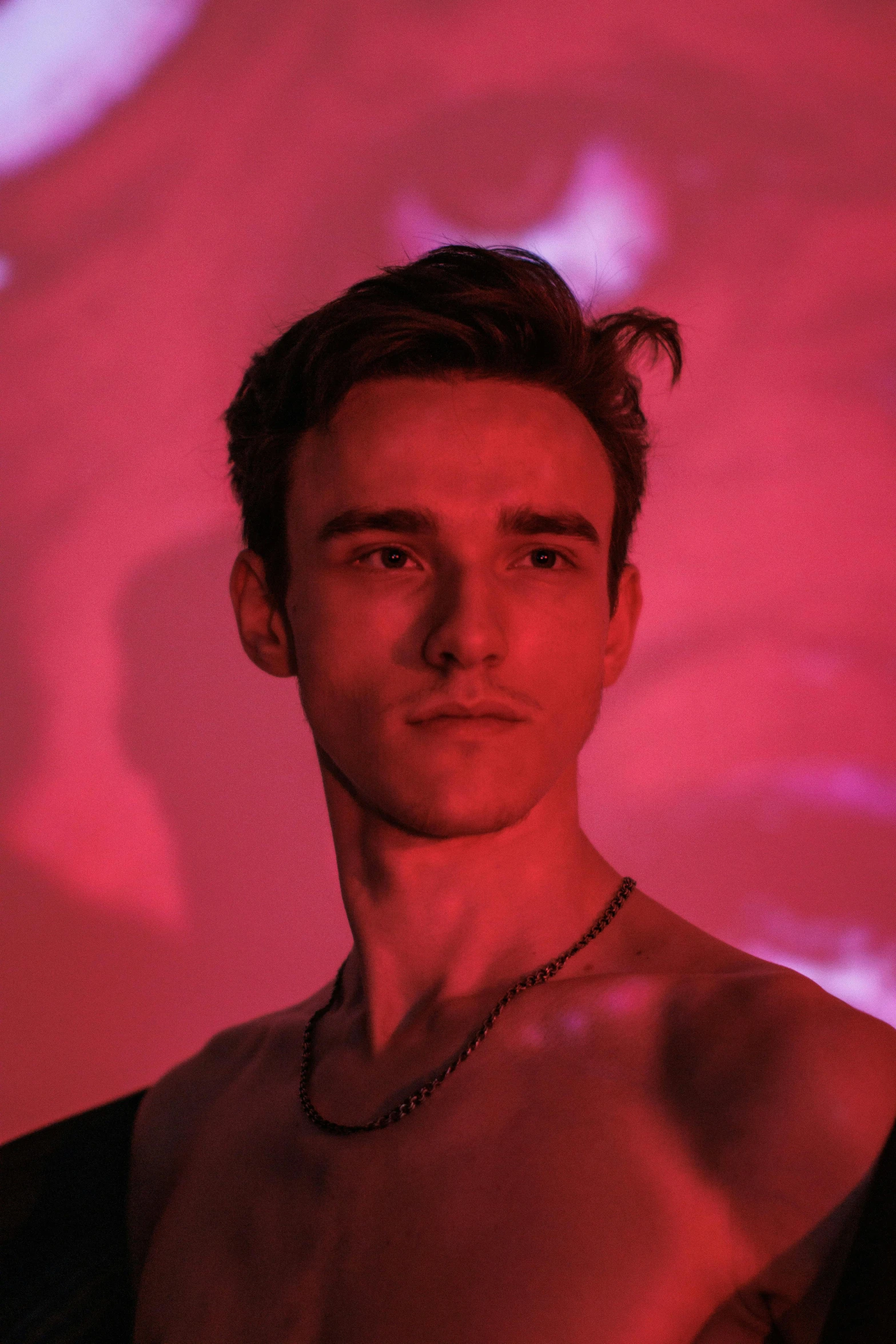 a man posing for a po in front of a pink light