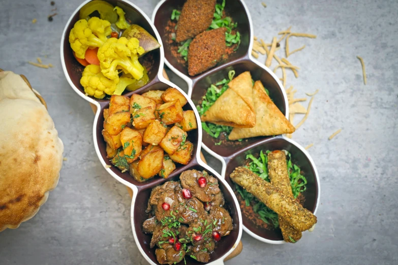 six black bowls with food and a pastry