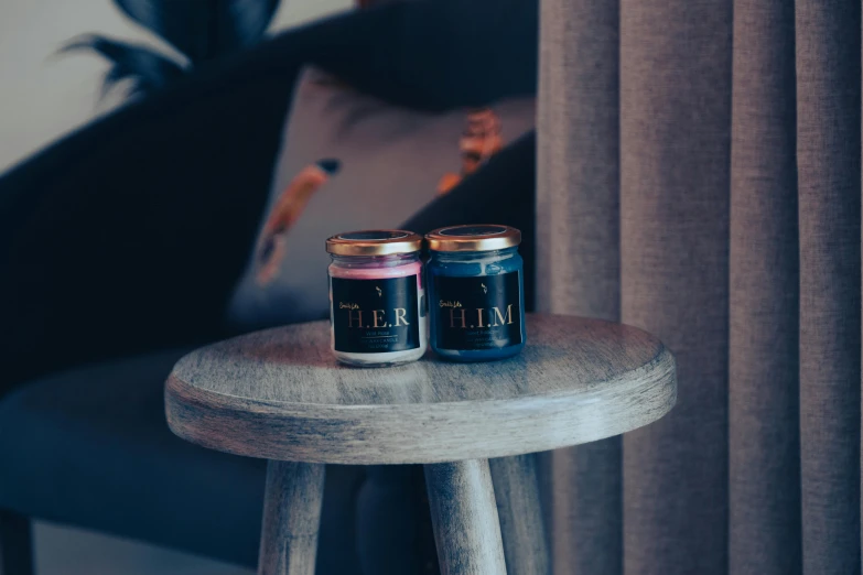 two candles on a stool next to a curtain