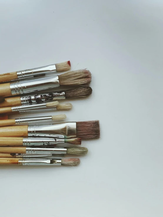 six paint brushes lined up on a table