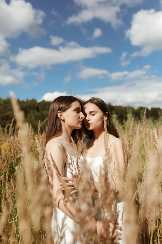 two women posing in the tall grass with their heads together