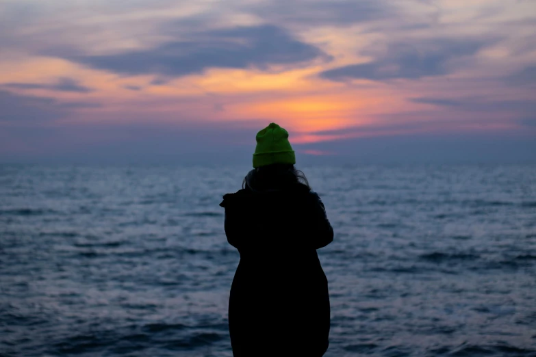 a person in the distance standing on a beach at sunset