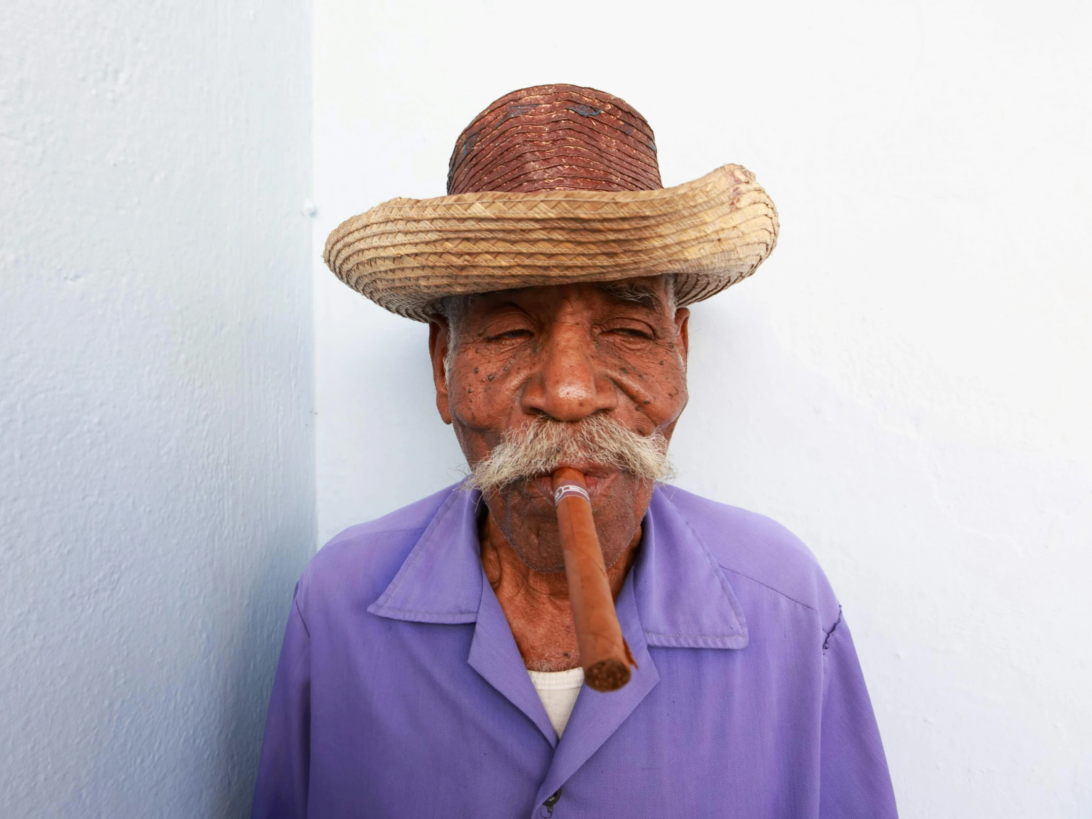 a man with a pipe in his mouth and purple shirt