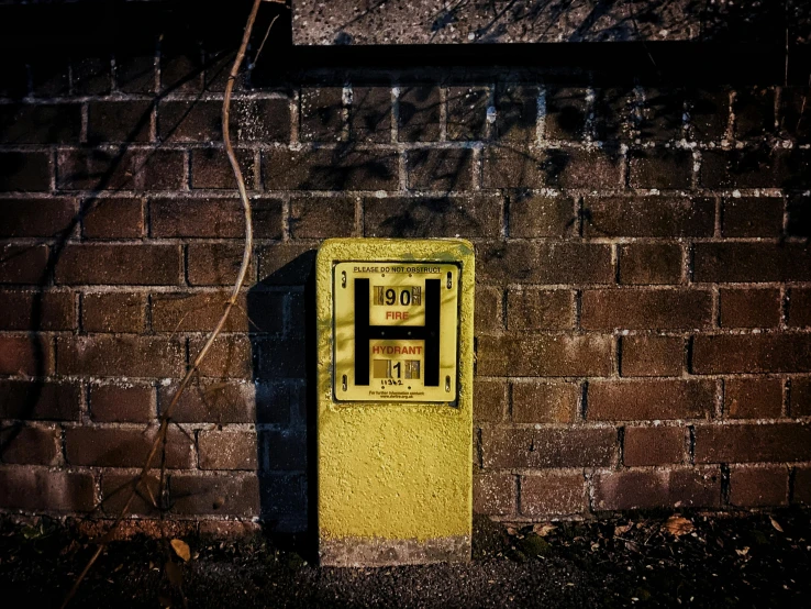 a yellow phone is on a brick wall