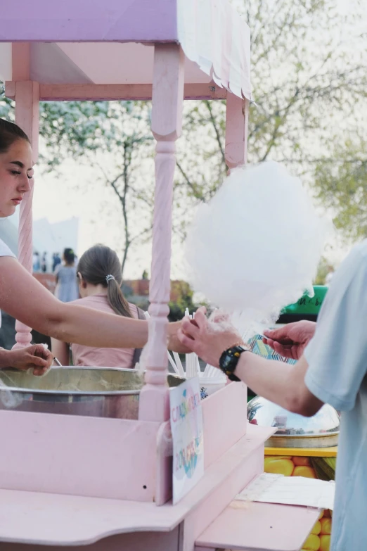 a girl handing soing to another person in a pink and purple cart