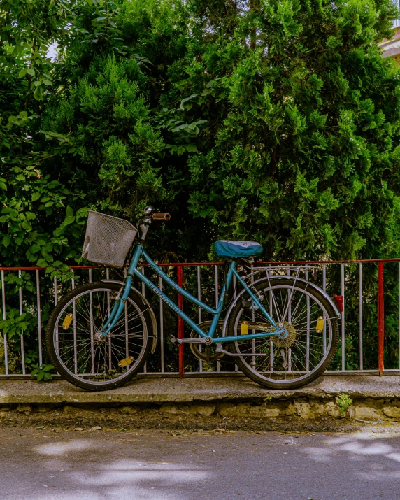 a blue bicycle  to a wrought iron fence