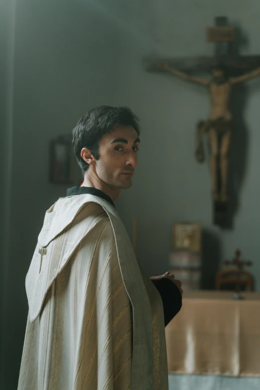 a man wearing a priest outfit in front of a cross