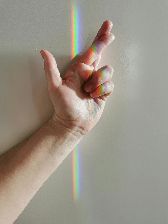 a hand with a rainbow painted on it is pointing to the side