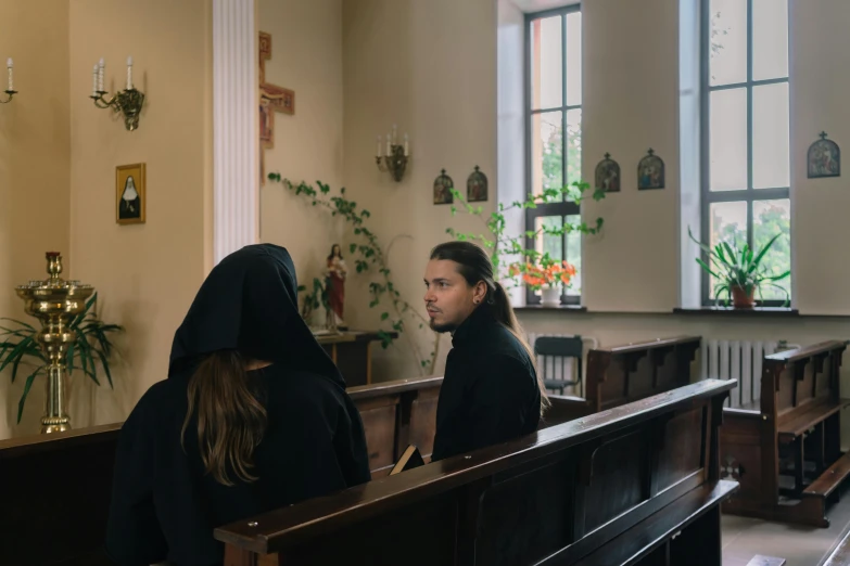 a couple sitting on pews in front of a window