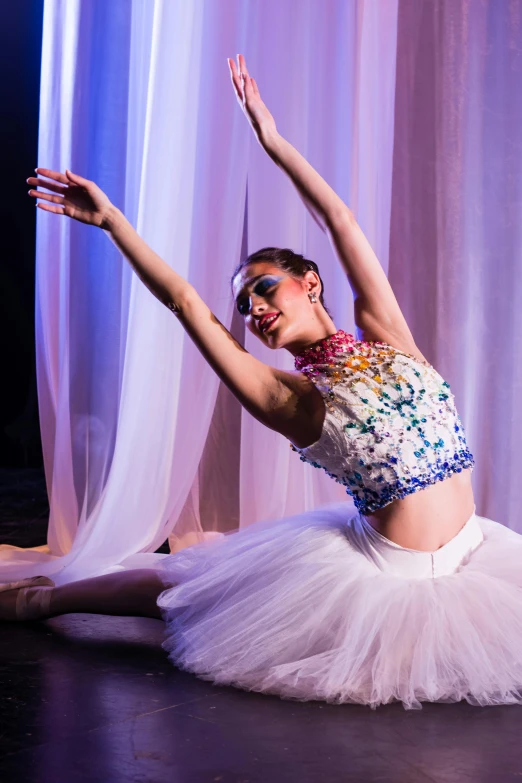 a dancer sitting on the floor with her arms stretched out in the air