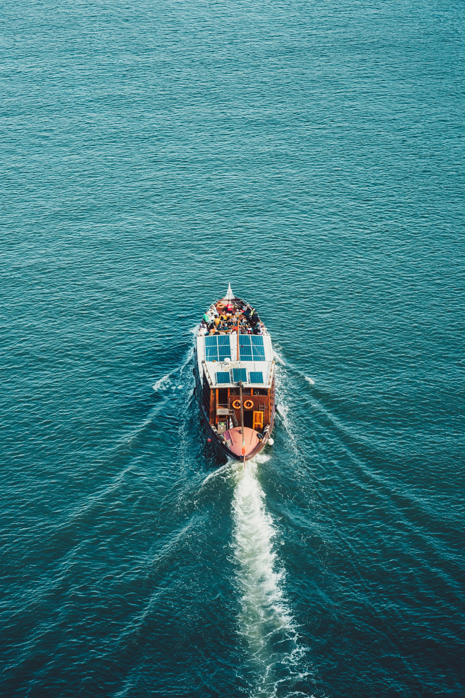 a ship with people is moving along a very large body of water