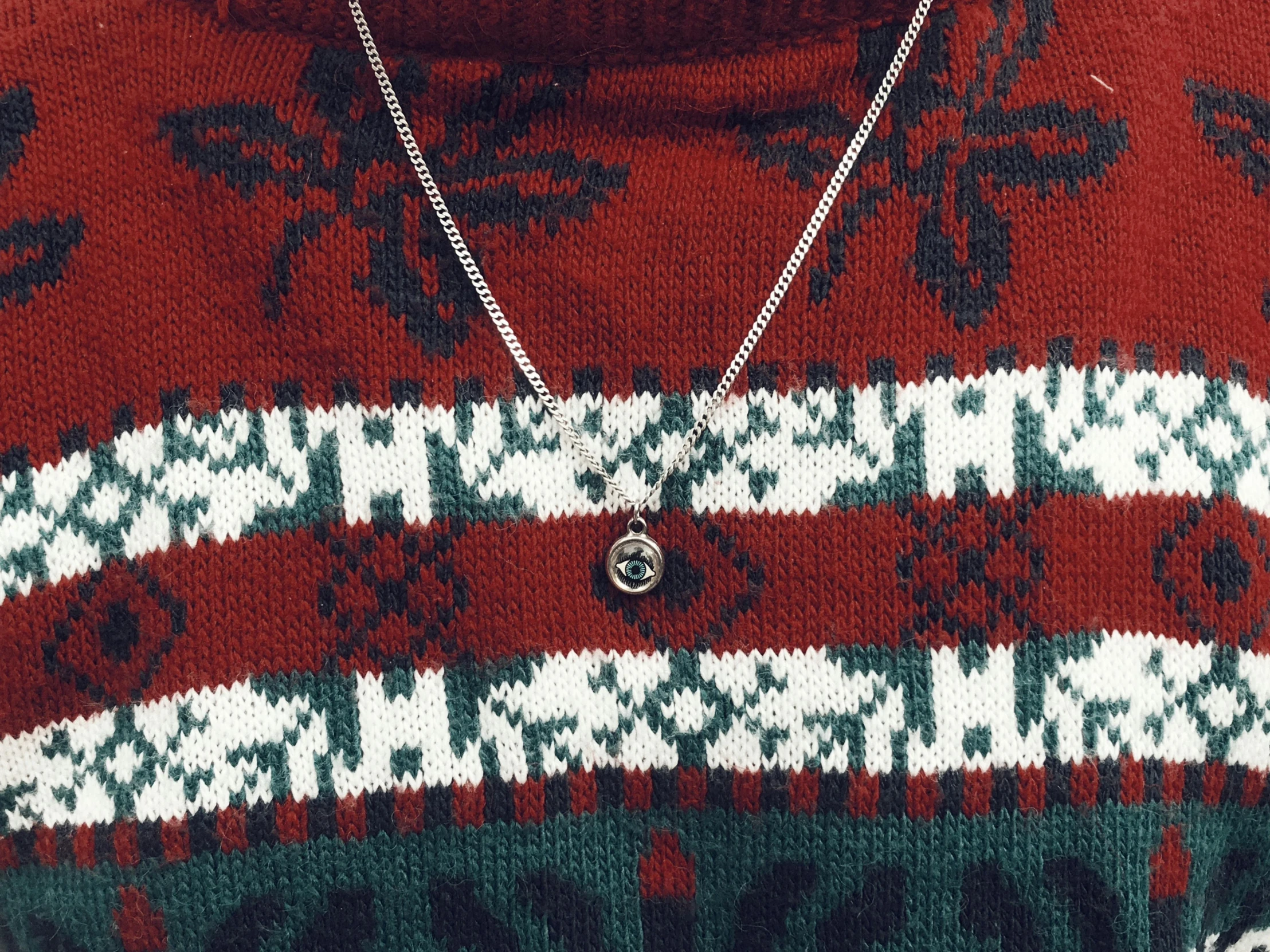 a person wearing a christmas sweater and wearing a large necklace