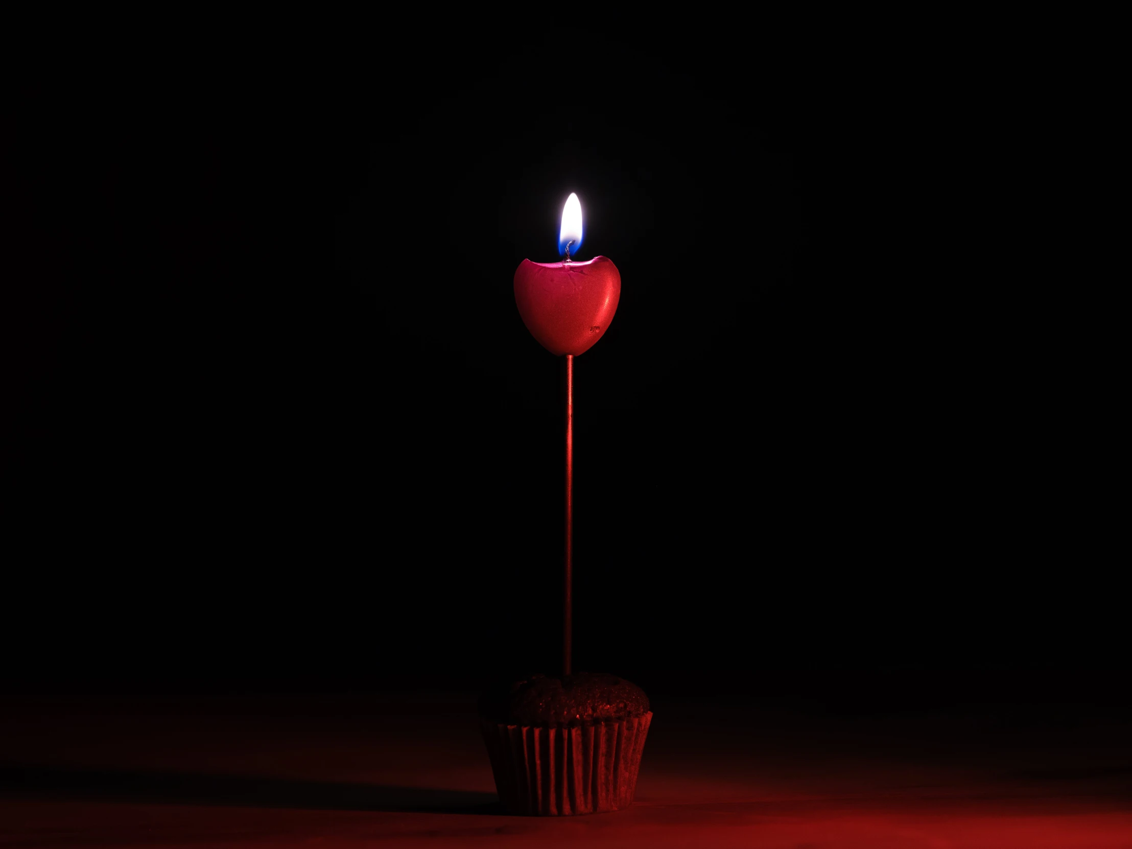 a cupcake with a candle burning next to it