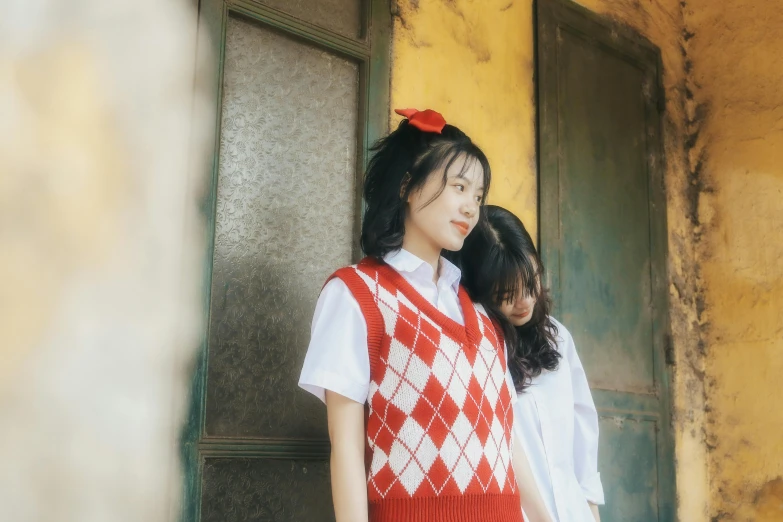 two asian women dressed in clothing standing in front of green door