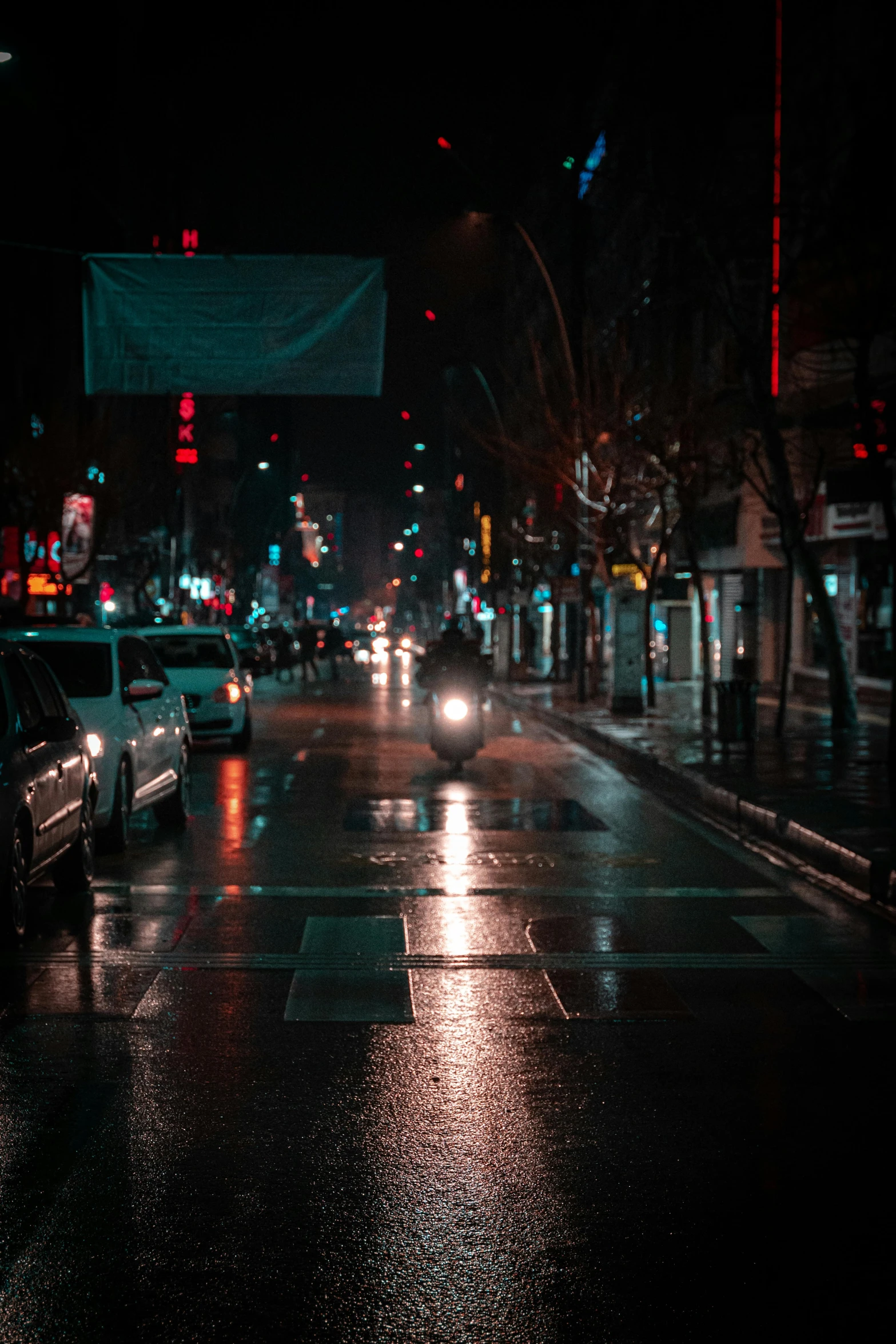 a city street at night with cars driving down it