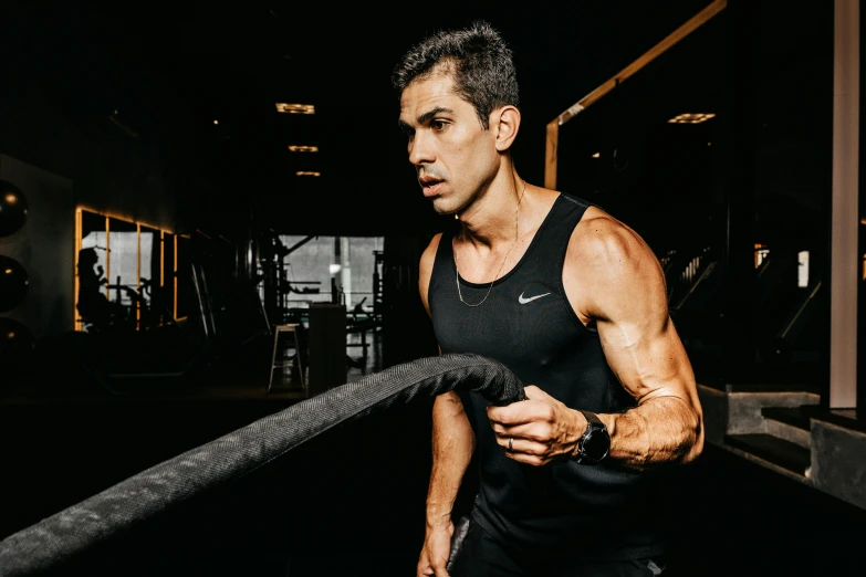 a man standing in a gym holding a rope