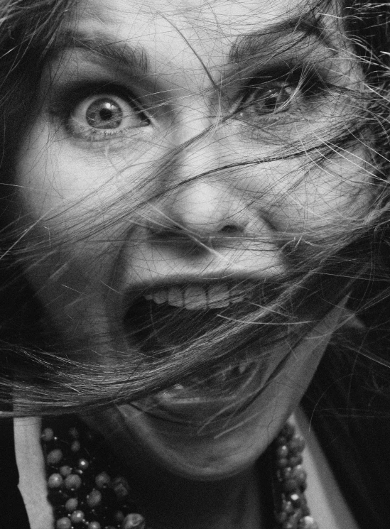 a black and white image of a woman holding her hair over her face