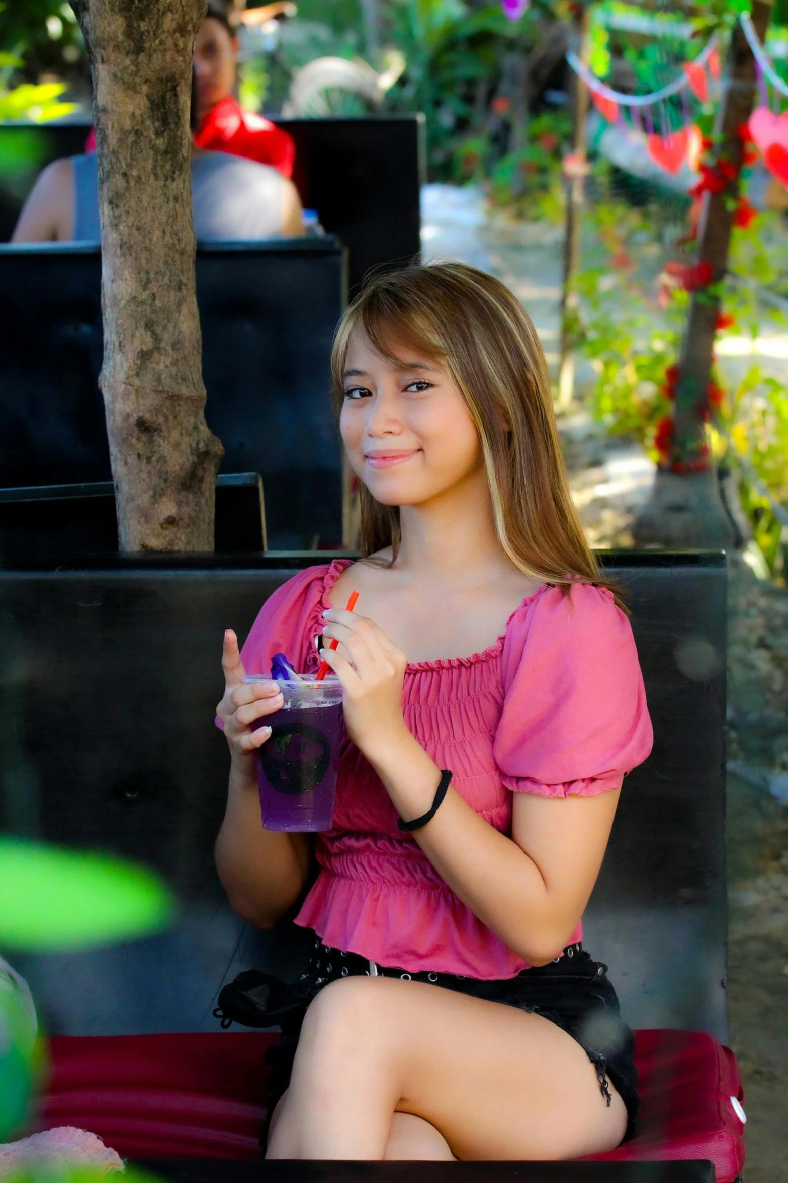 young woman in pink dress eating and drinking at outdoor event