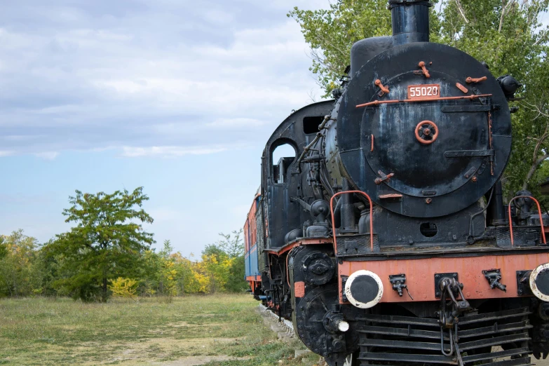 an old steam engine is sitting outside by trees